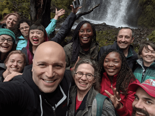 Small group of CivicActions team members smiling by a waterfall in Portland, Oregon
